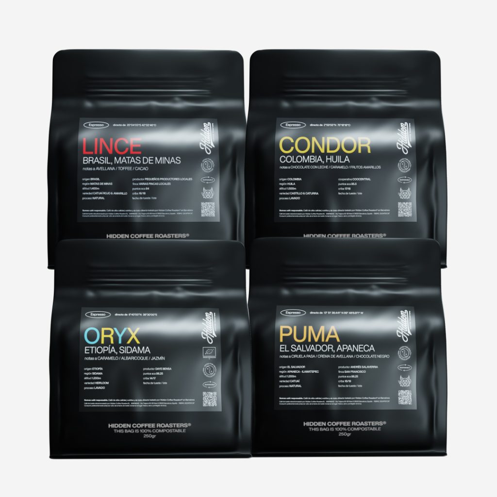 Pack de 4 bolsas de café en grano Hidden Coffee Roasters de 250 gramos: Lince (Brasil, Matas de Minas), Cóndor (Colombia, Huila), Oryx (Etiopía, Sidama) y Puma (El Salvador, Apaneca), en envase negro compostable con etiqueta de origen y notas de cata.