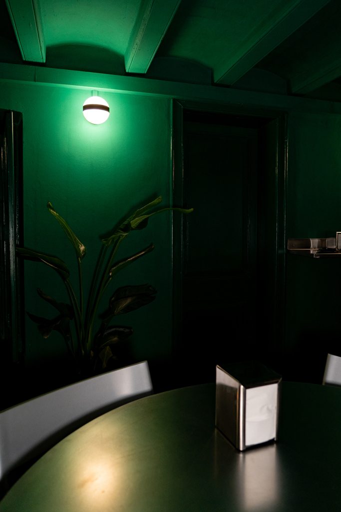 Sala interior piso inferior en Granja Hidden, en tonos verdes y mobiliario a medida en inox