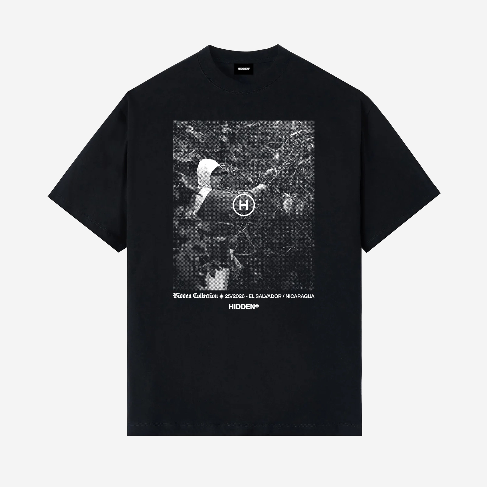 Vista delantera de camiseta negra Hidden Collection con fotografía en blanco y negro de un recolector de café entre plantas, y texto "El Salvador / Nicaragua"