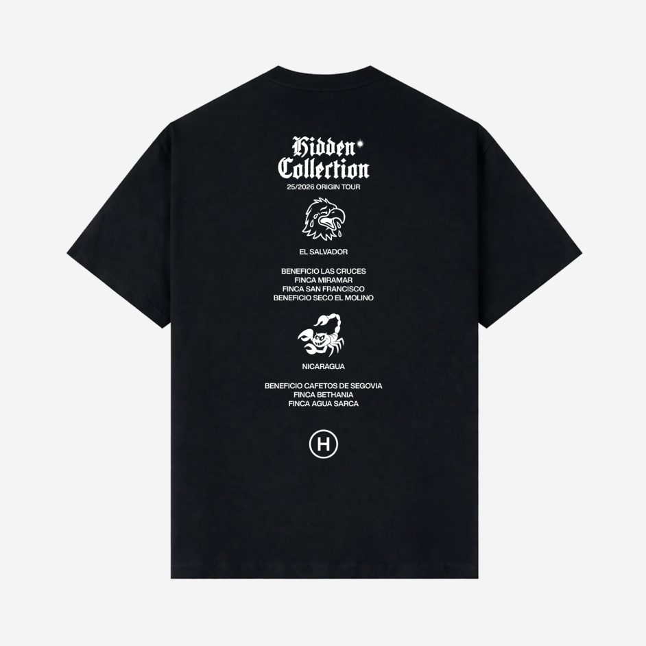 Parte trasera de camiseta negra Hidden Collection con diseño gráfico de águila y escorpión, textos en blanco con tipografía gótica y referencias a fincas de El Salvador y Nicaragua
